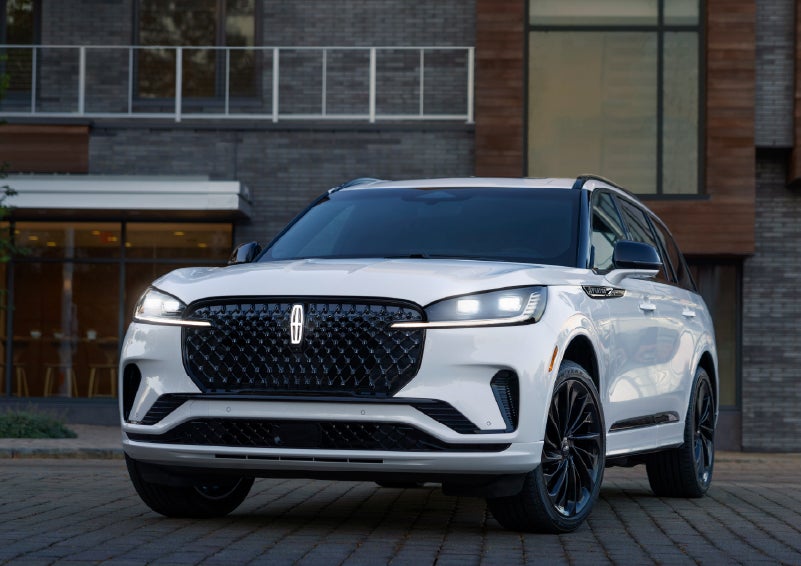 A 2026 Lincoln Aviator® Reserve model is shown with the available Jet Appearance Package parked near a restaurant. | Krenzen Lincoln in Duluth MN