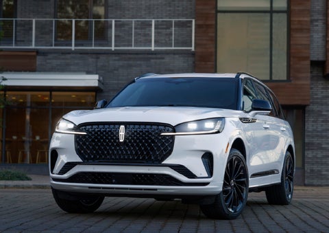 A 2026 Lincoln Aviator® Reserve model is shown with the available Jet Appearance Package parked near a restaurant. | Krenzen Lincoln in Duluth MN