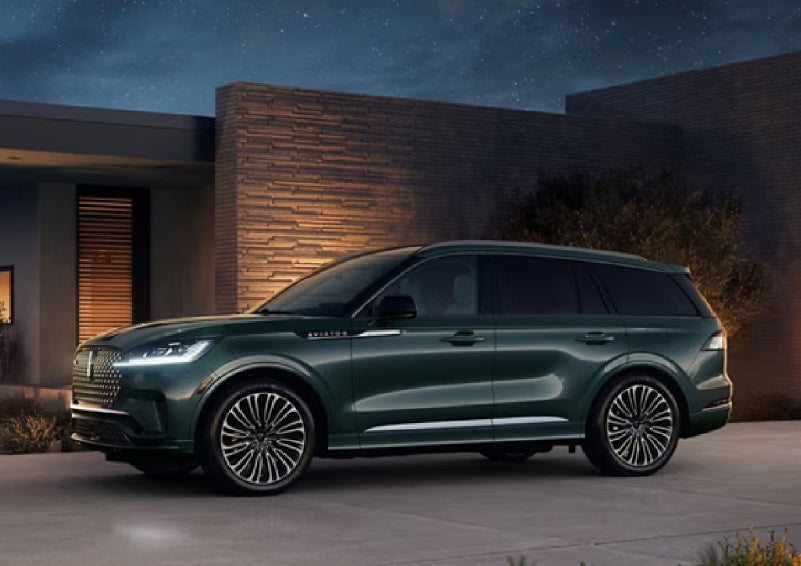 A green 2027 Lincoln Aviator® SUV is parked outside a contemporary home. | Krenzen Lincoln in Duluth MN