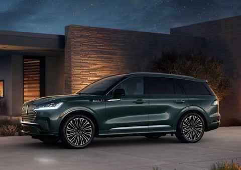 A green 2027 Lincoln Aviator® SUV is parked outside a contemporary home. | Krenzen Lincoln in Duluth MN