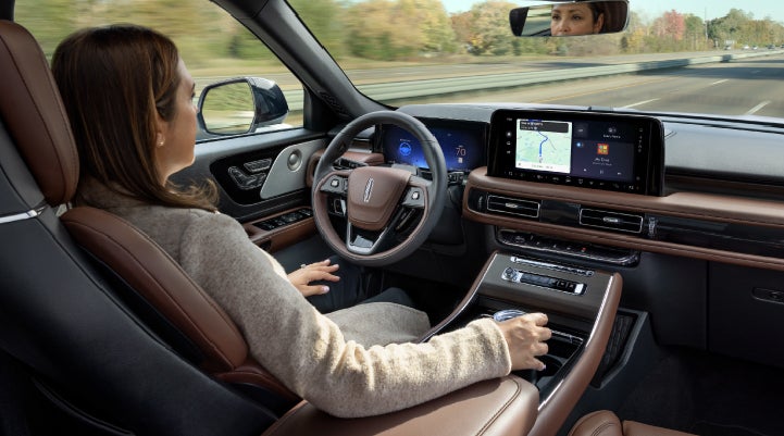 A 2027 Lincoln Aviator® SUV is being driven hands-free on a highway lined with trees. | Krenzen Lincoln in Duluth MN