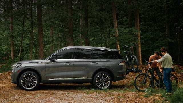 A father and son load e-bikes on a bike rack attached to a 2027 Lincoln Aviator® SUV. | Krenzen Lincoln in Duluth MN
